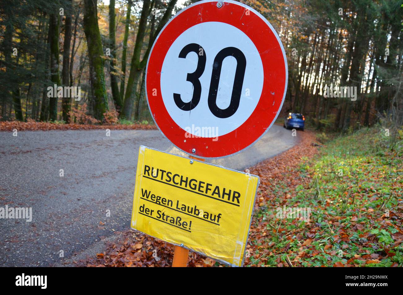 Schild Rutschgefahr im Herbst auf einer Straße in Österreich, Europa - Schilderrutschgefahr im Herbst auf einer Straße in Österreich, Europa Stockfoto