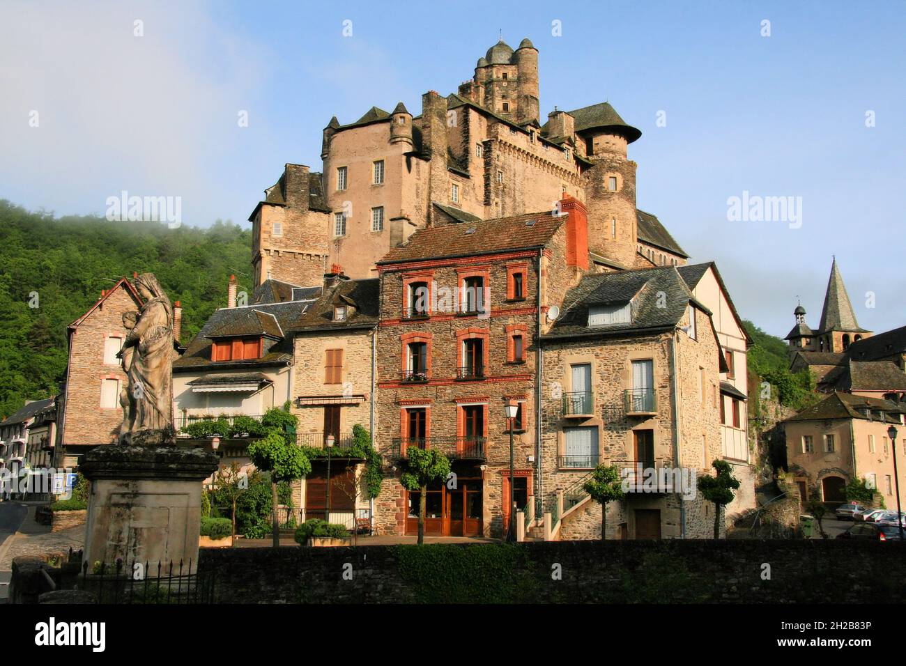 Schloss Estaing (Schloss), Gebäude aus der Zeit, Statue und Kirche vom Ufer des Flusses Lot kurz nach Sonnenaufgang in Estaing, Aveyron, Oczitanie, Frankreich Stockfoto