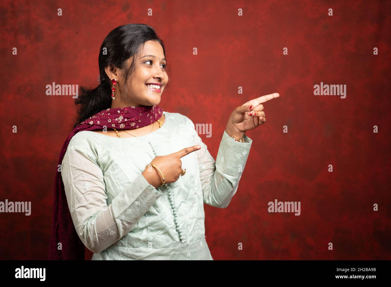 Glücklich lächelnde indische Frau zeigt den Finger auf leeren Raum - Koknept der Anzeige von Angeboten oder Rabatten für Festival-Verkäufe Werbung mit Kopierraum. Stockfoto