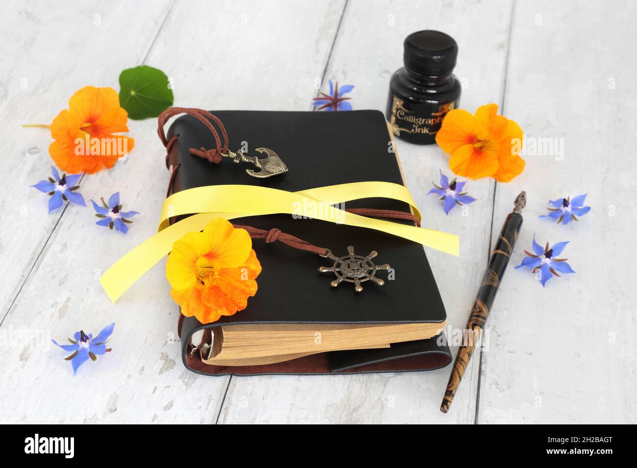 Tagebuch oder Notizbuch für private Gedanken, Träume oder Manuskriptkonzept mit Blumen, altem Stift und Tintenflasche auf rustikalem Holzhintergrund. Stockfoto