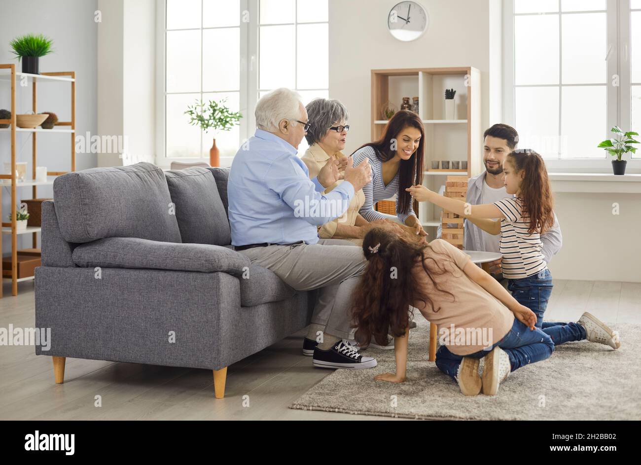 Glückliche Mutter, Vater, Großmutter, Großvater und Kinder spielen Brettspiel zu Hause Stockfoto