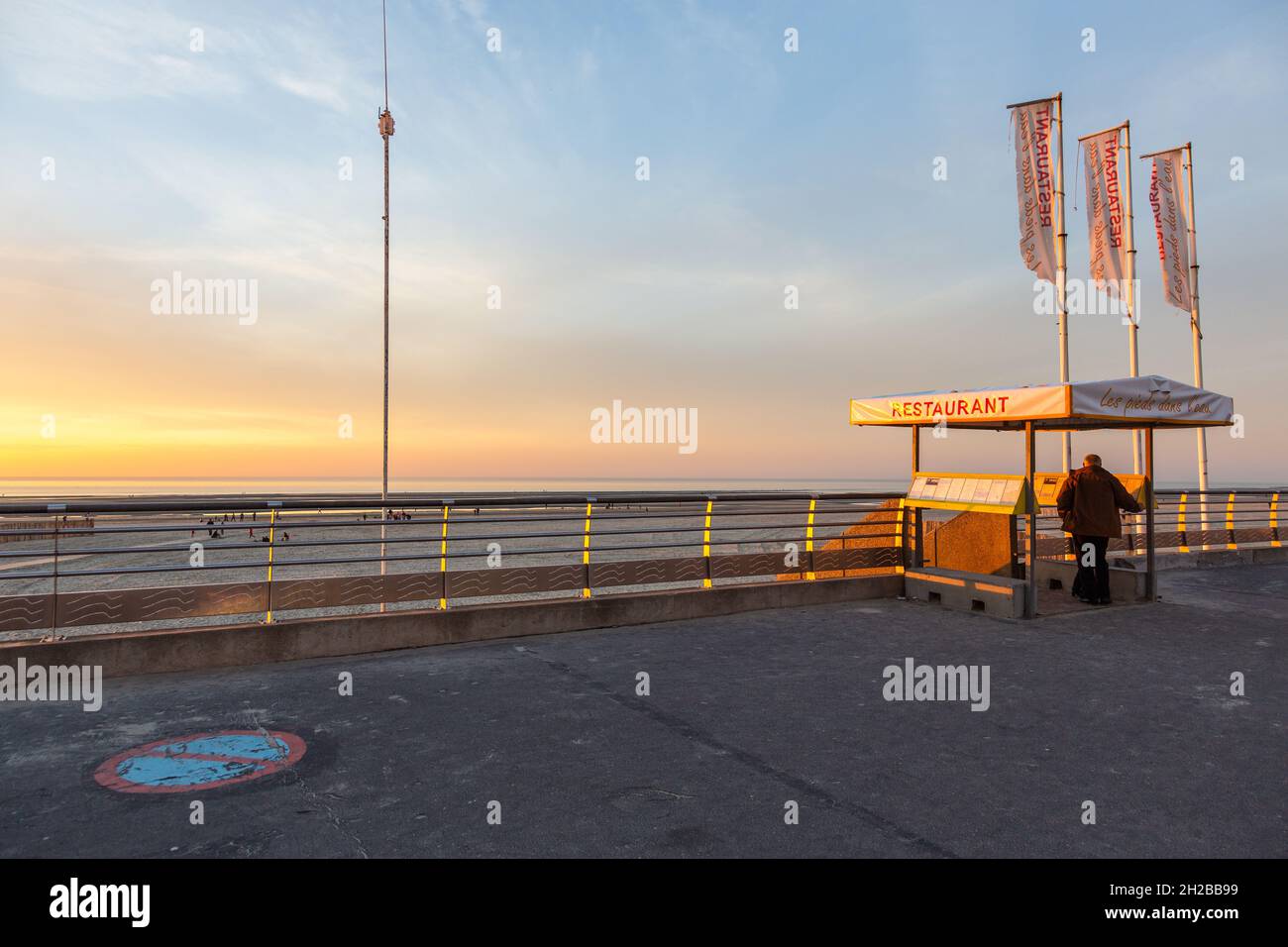 Deich von Berck-Plage bei Sonnenuntergang, Eingang zum Restaurant, Mann schaut auf die Speisekarte. Opal Coast, Frankreich Stockfoto