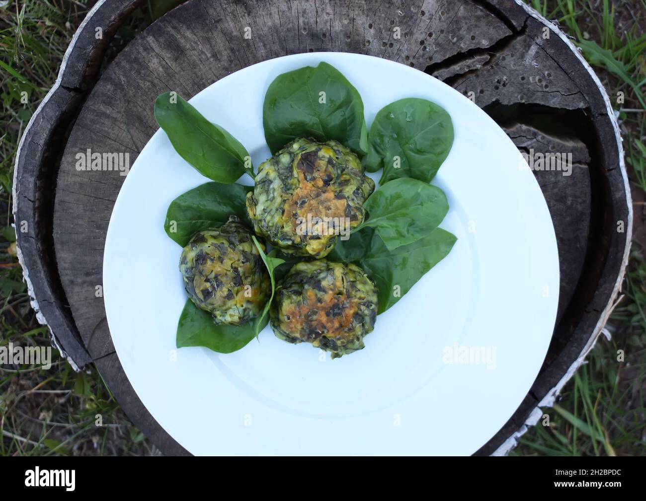 Spinatpfannkuchen mit grünen Spinatblättern auf einem Baumstumpf im Freien Stockfoto