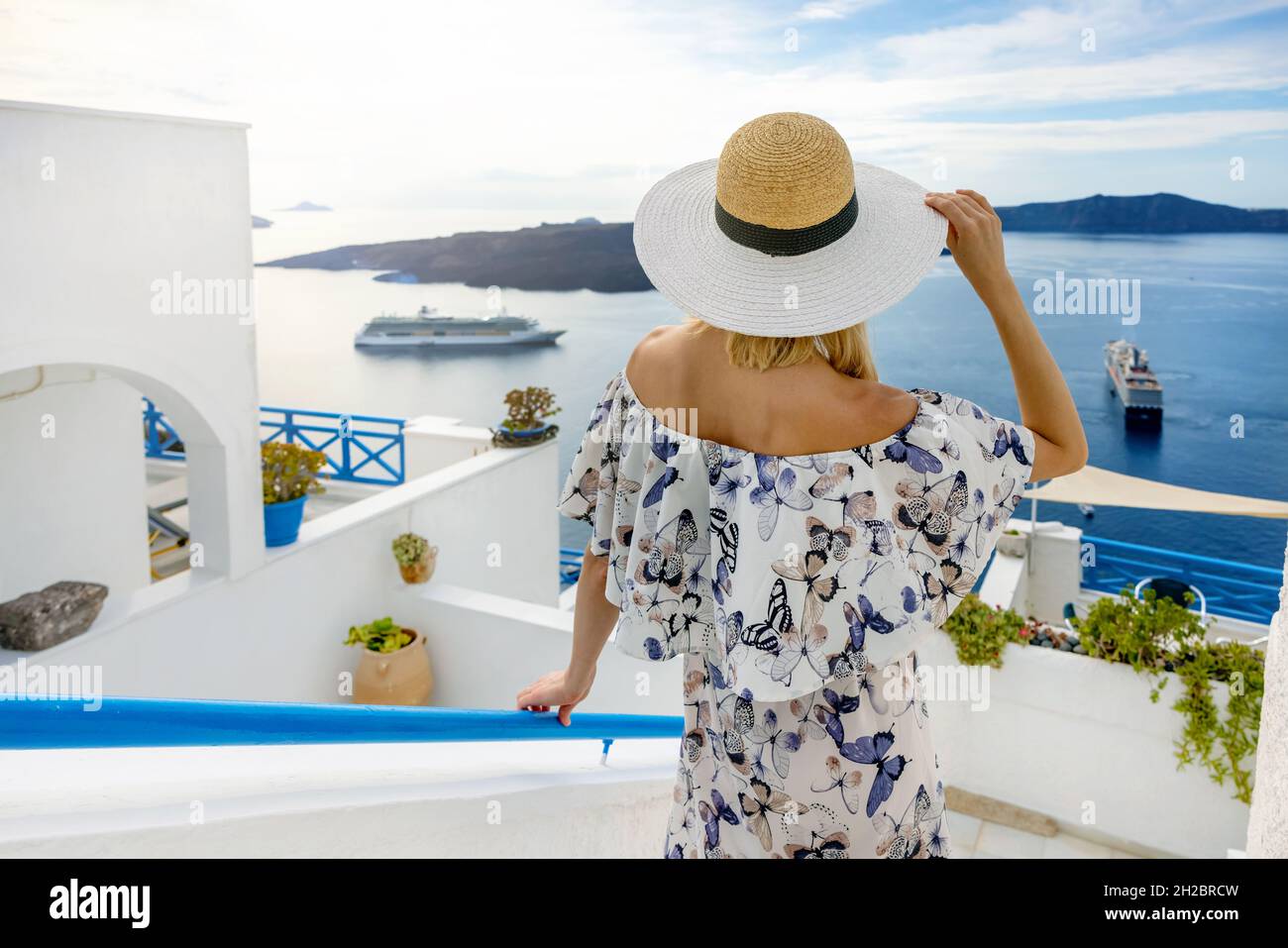 Frau auf Santorini, die auf die Kreuzfahrt-Schiffe in der ägäis schaut. Griechische Inseln Stockfoto