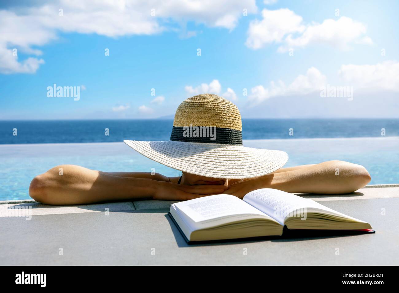 Frau versteckt sich unter Strohhut und ruht im unendlichen Pool. Entspannender Sommerurlaub im Resort Stockfoto Frau versteckt sich unter Strohhut und ruht im unendlichen Pool. Entspannender Sommerurlaub im Resort Stockfoto