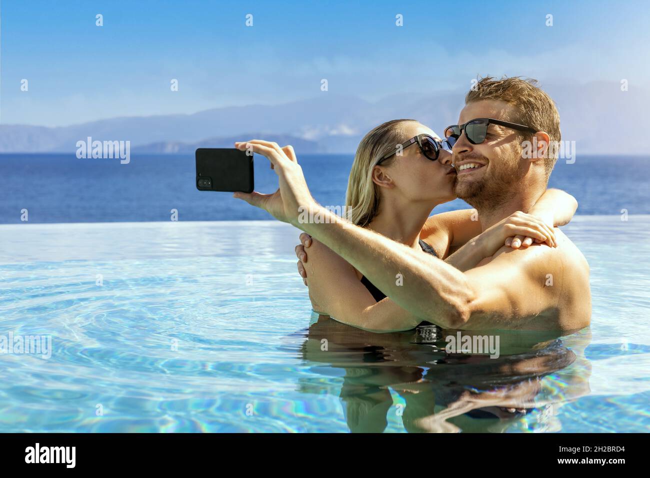 Junges Paar in der Liebe unter Selfie im Unendlichen Pool. Romantischer Kurzurlaub, Sommerurlaub Stockfoto