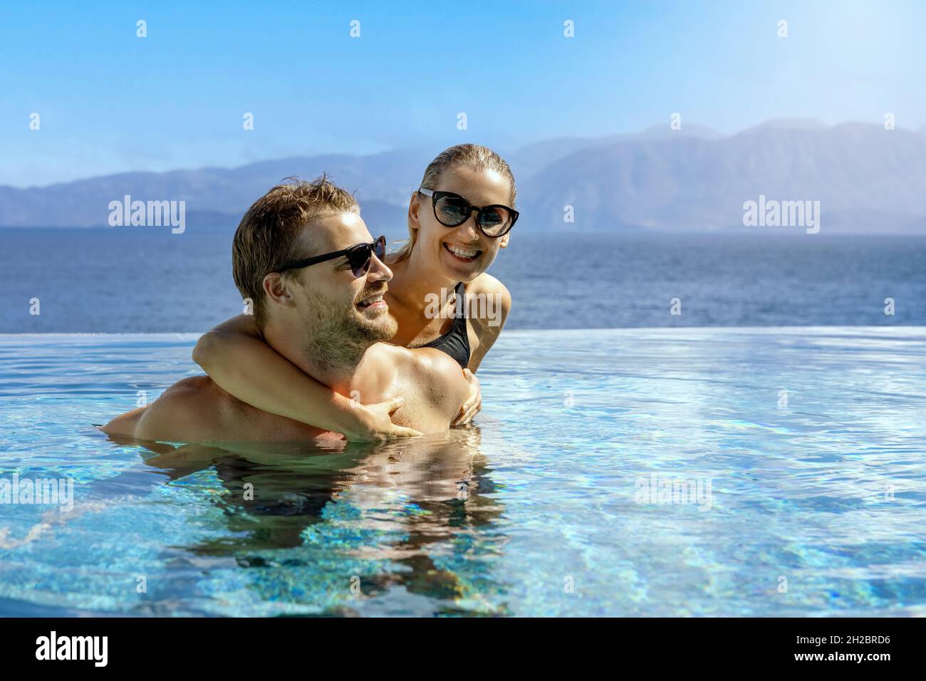 Glücklich lächelndes junges Paar, das Spaß zusammen im Unendlichen Swimmingpool hat. Romantischer Sommerurlaub Stockfoto
