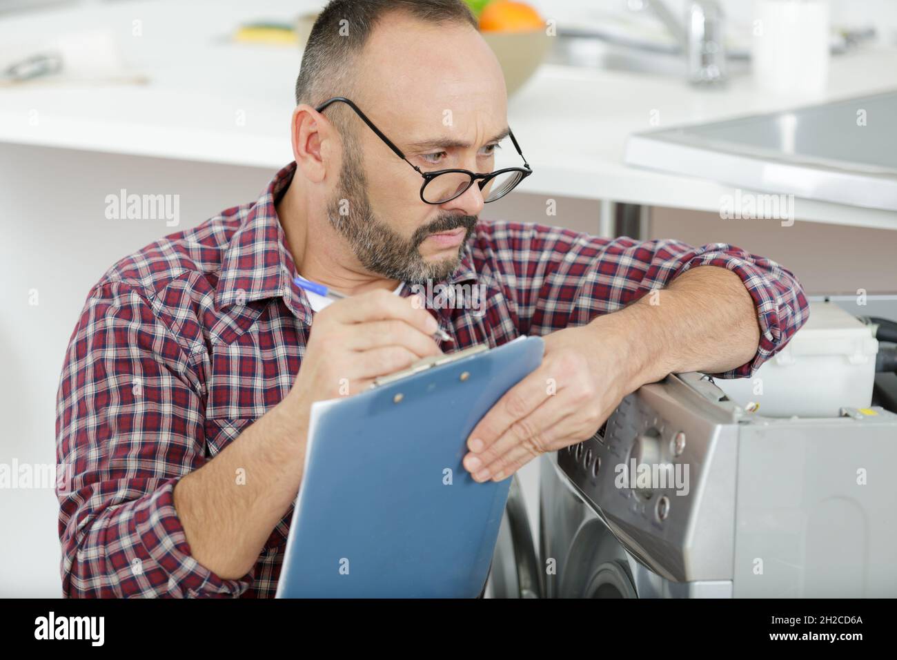 Der Wartemann der Waschmaschine schaute über die Gläser, um zu schreiben Stockfoto