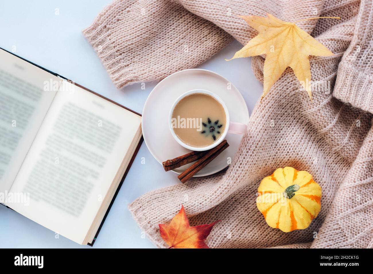 Heißer Kaffee mit Sternanise und Zimt in einer Tasse, einem offenen Buch, einem gelben Kürbis und Herbstblättern. Draufsicht, flach liegend. Herbstkonzept. Stockfoto