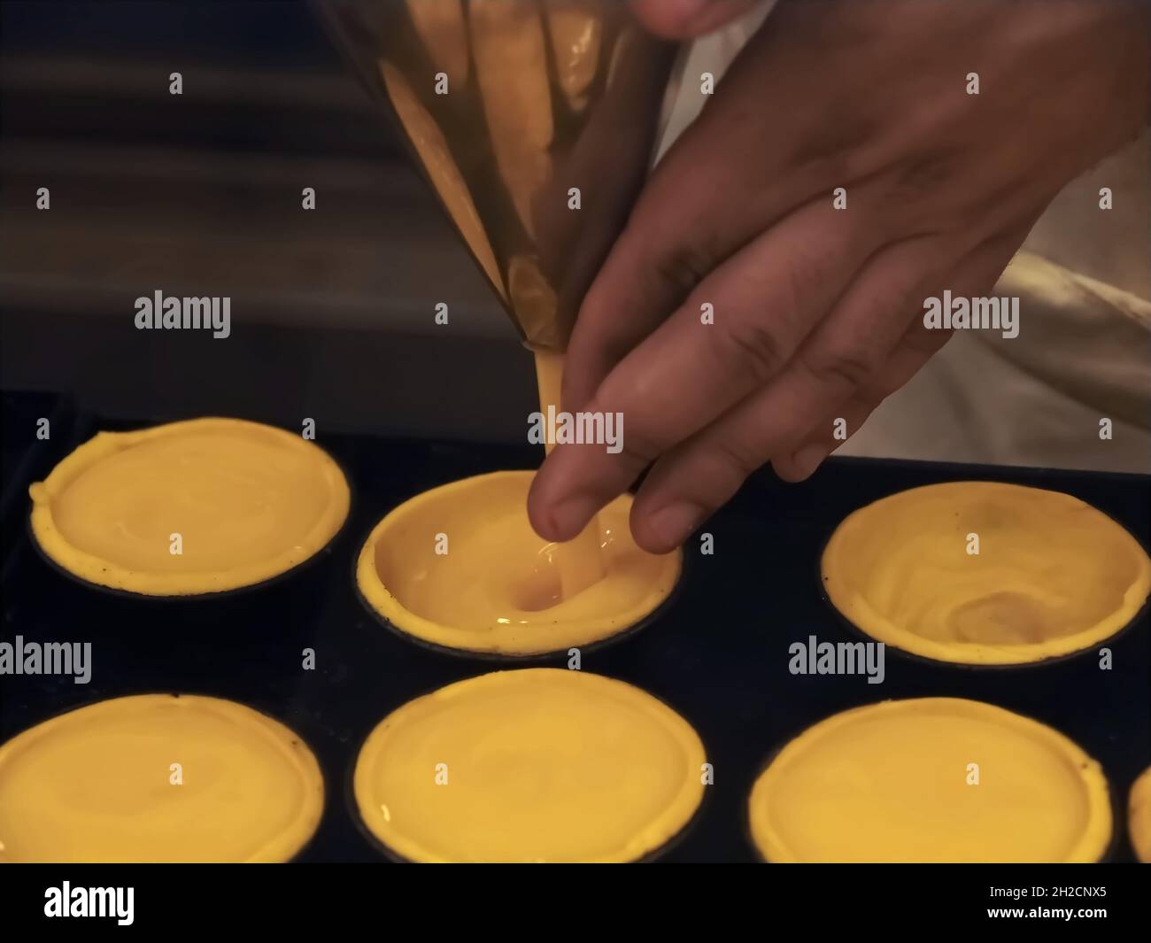 Bäckerei von leckeren portugiesischen pastei de nata - Bäcker füllt sich mit Pudding Stockfoto