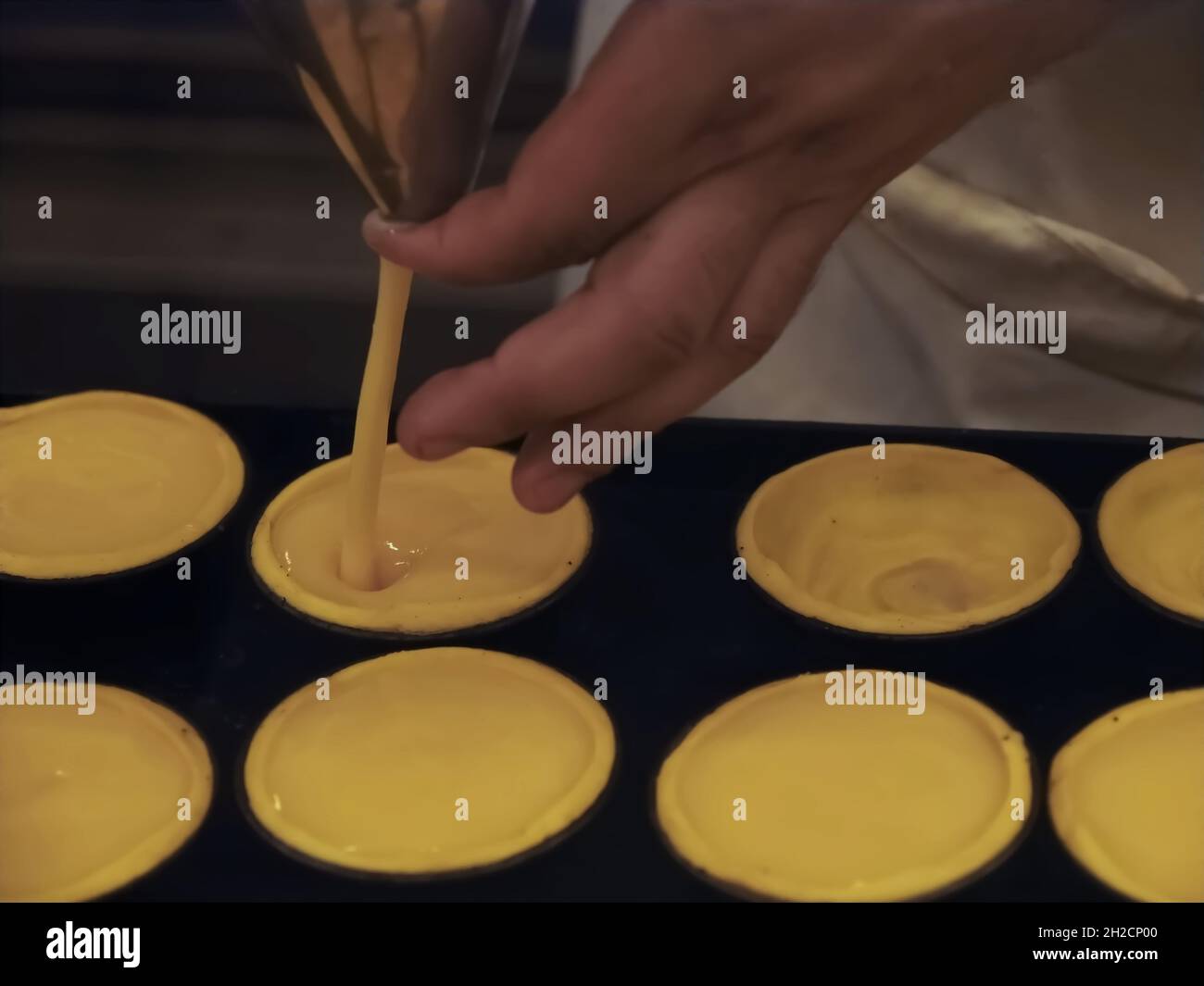 Bäckerei von leckeren portugiesischen pastei de nata - Bäcker füllt sich mit Pudding Stockfoto