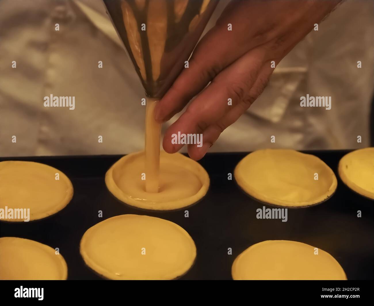 Bäckerei von leckeren portugiesischen pastei de nata - Bäcker füllt sich mit Pudding Stockfoto