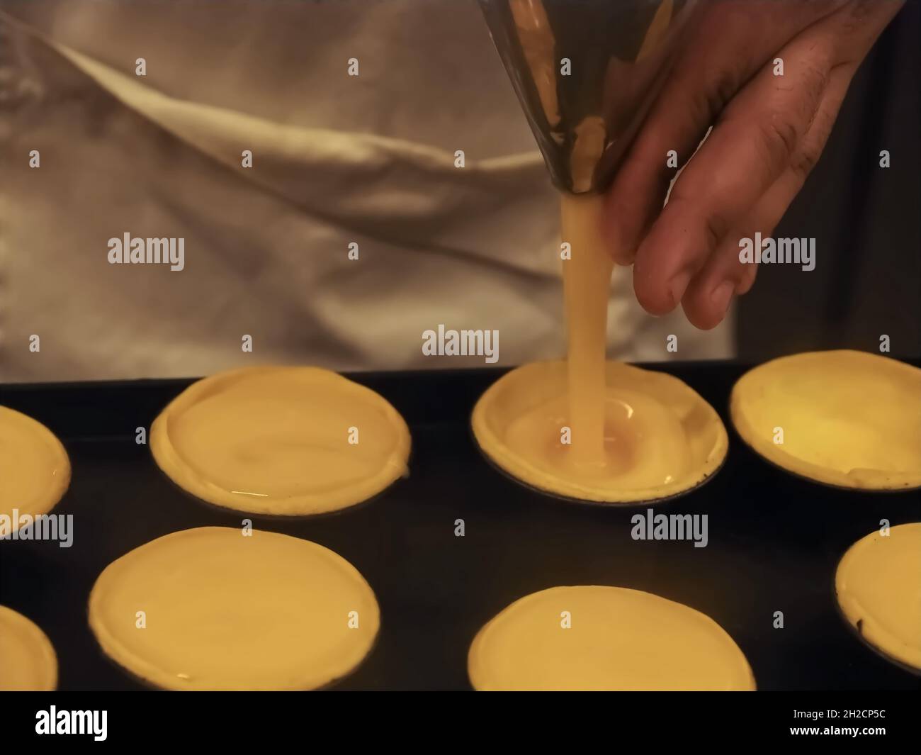 Bäckerei von leckeren portugiesischen pastei de nata - Bäcker füllt sich mit Pudding Stockfoto