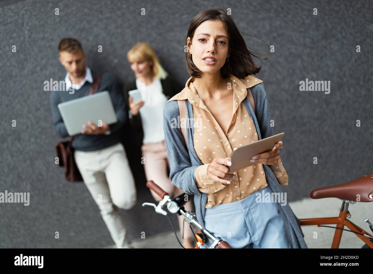 Gruppe glücklicher junger Geschäftsleute, die verschiedene digitale Geräte im Freien halten. Stockfoto