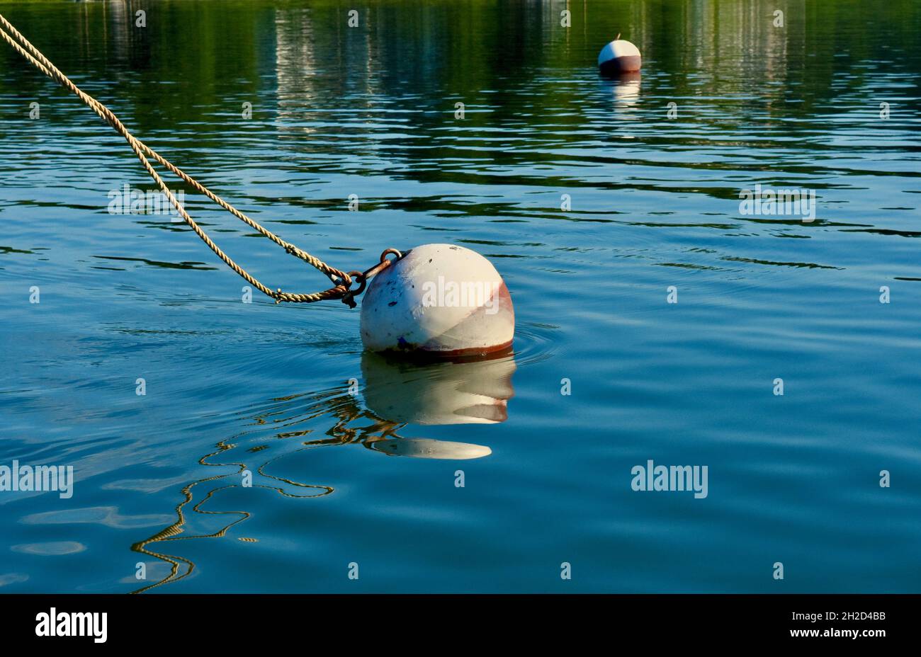 Festmachen Ball Verankerung Linien von einem unsichtbaren Boot. Wasser ist ein lebhaftes Blau mit interessanten Oberflächenmustern. Speicherplatz kopieren. Hintergrund. Stockfoto