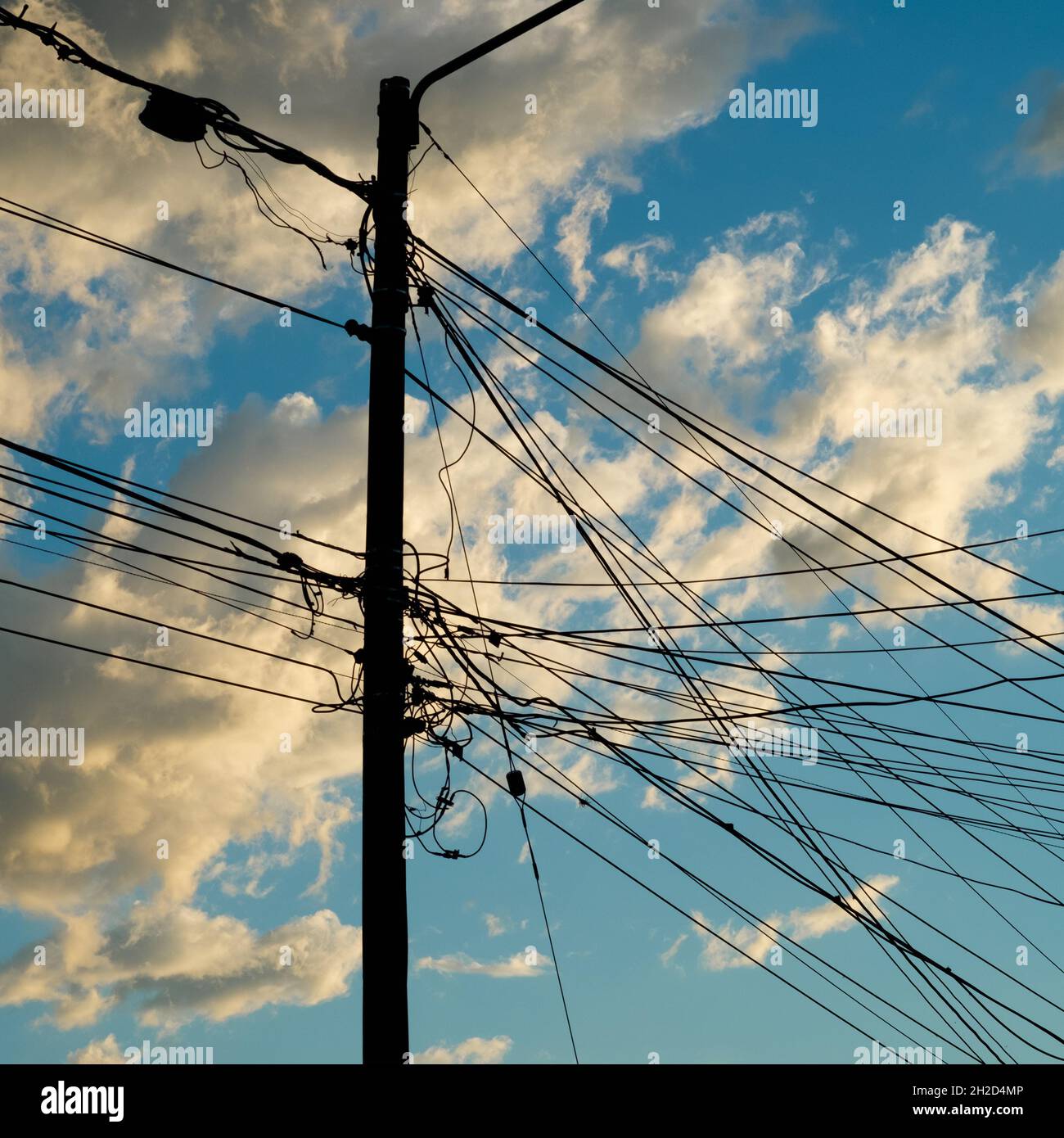 Verschmutzung der Kabel gegen einen klaren Himmel und weiße Wolken, irgendwo in Kolumbien. Stockfoto