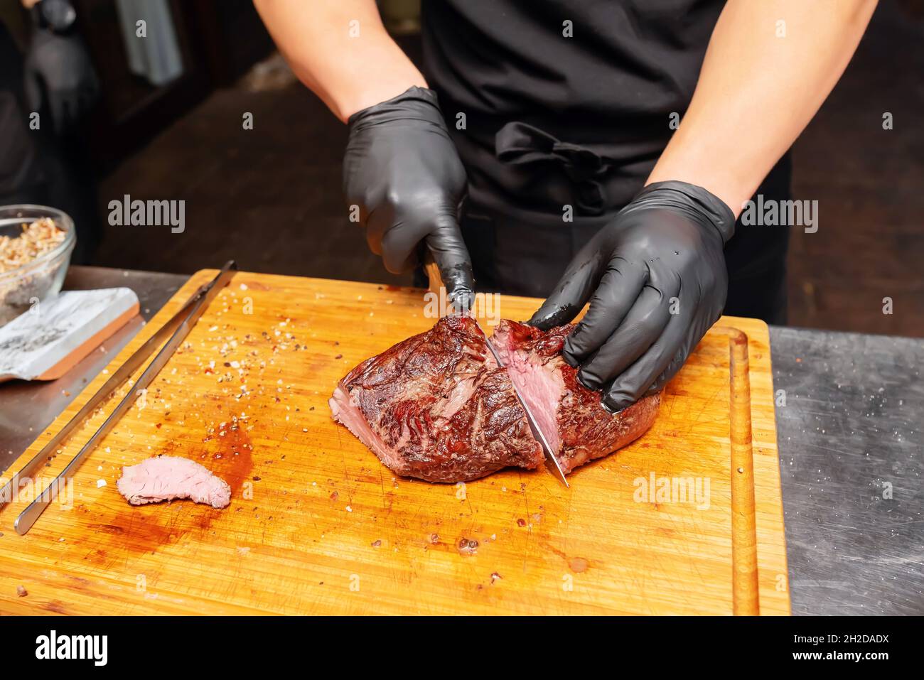 Cook schneidet ein Stück Roastbeef auf einem Brett Stockfoto
