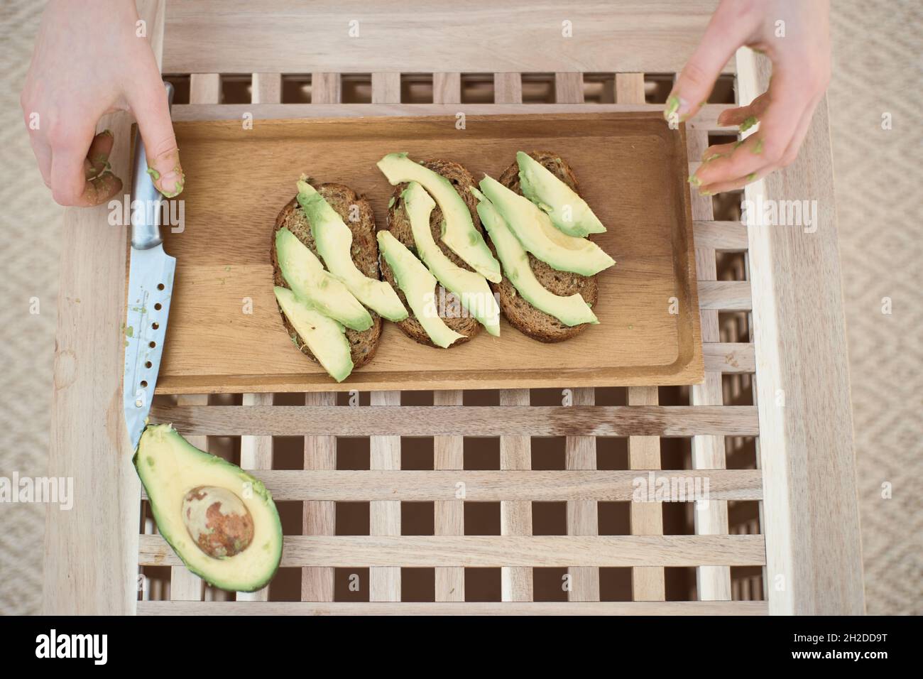 Draufsicht der jungen Frau legt das Messer nach dem Schneiden der Avocado Stockfoto