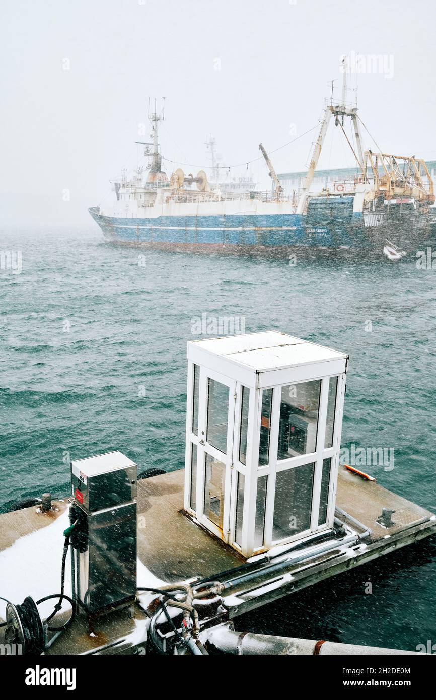 Schwimmende Anlegestelle mit Kraftstoffpumpe gegen Fischerboot, das bei nebelndem Wetter in Island auf dem welligen Meer festgemacht wurde Stockfoto