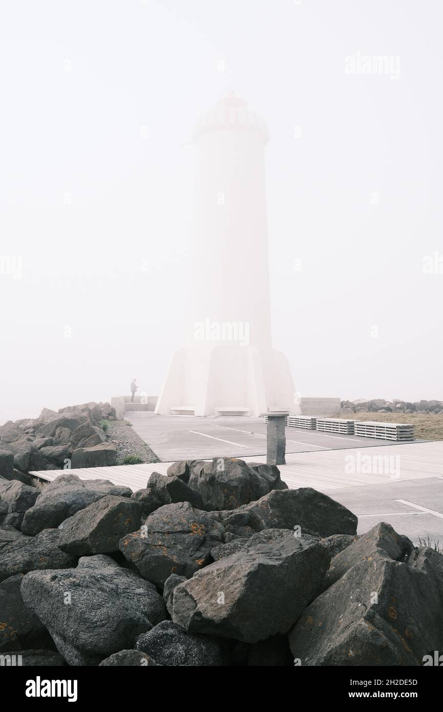 Kreatives Design von Leuchtfeuer gegen Steinhaufen und Gehweg unter hellem Himmel im Nebel in Island Stockfoto