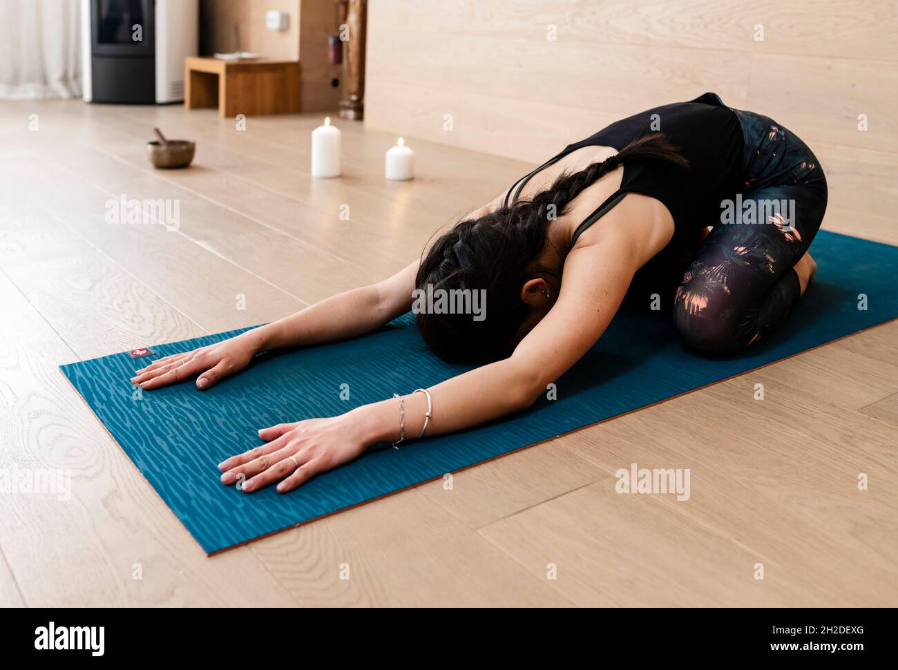 Die ganze Länge einer jungen Frau, die in Kinderpose auf einer Yogamatte sitzt Stockfoto