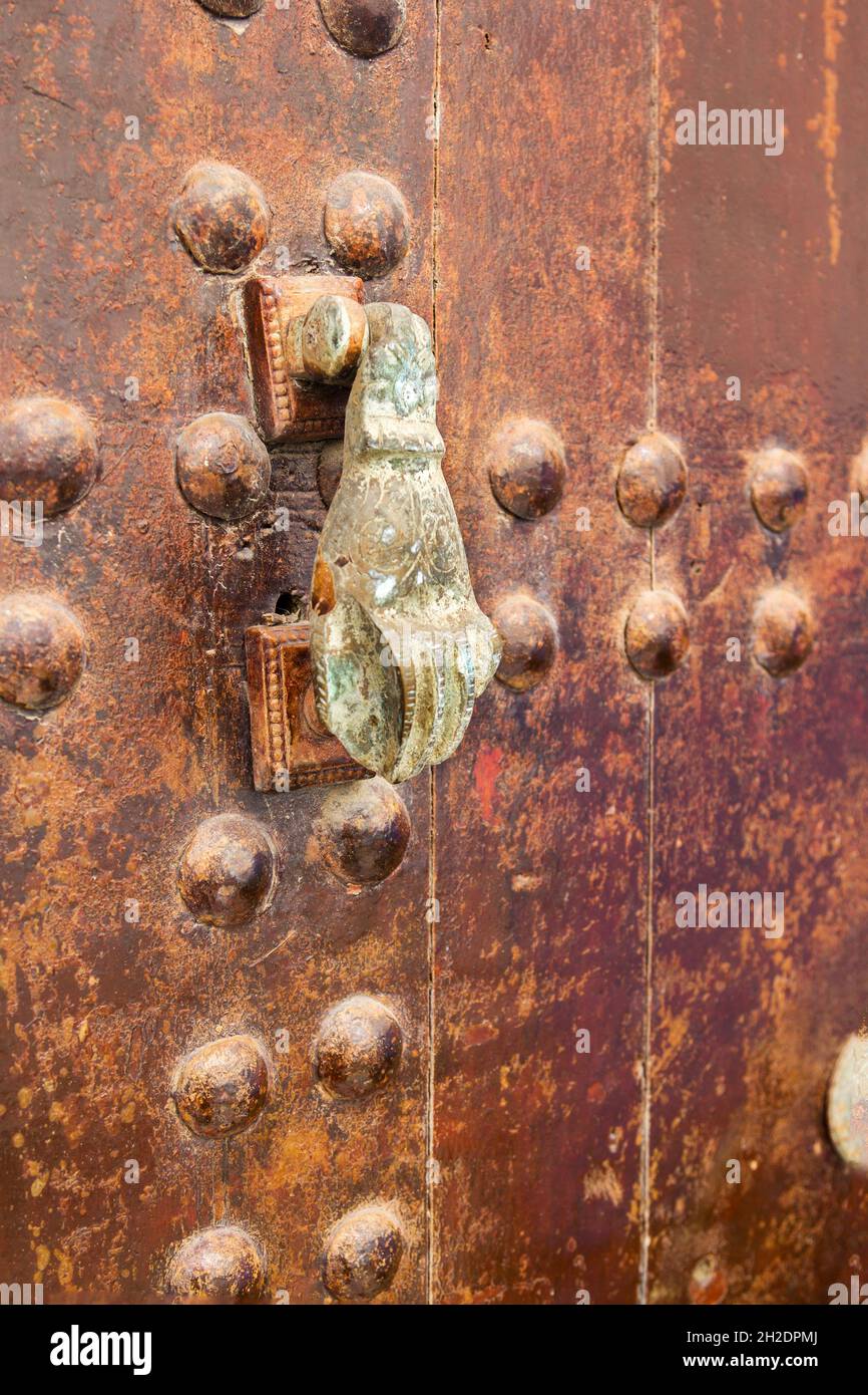 Eine rostige Handtür klopft an eine alte Holztür Stockfoto