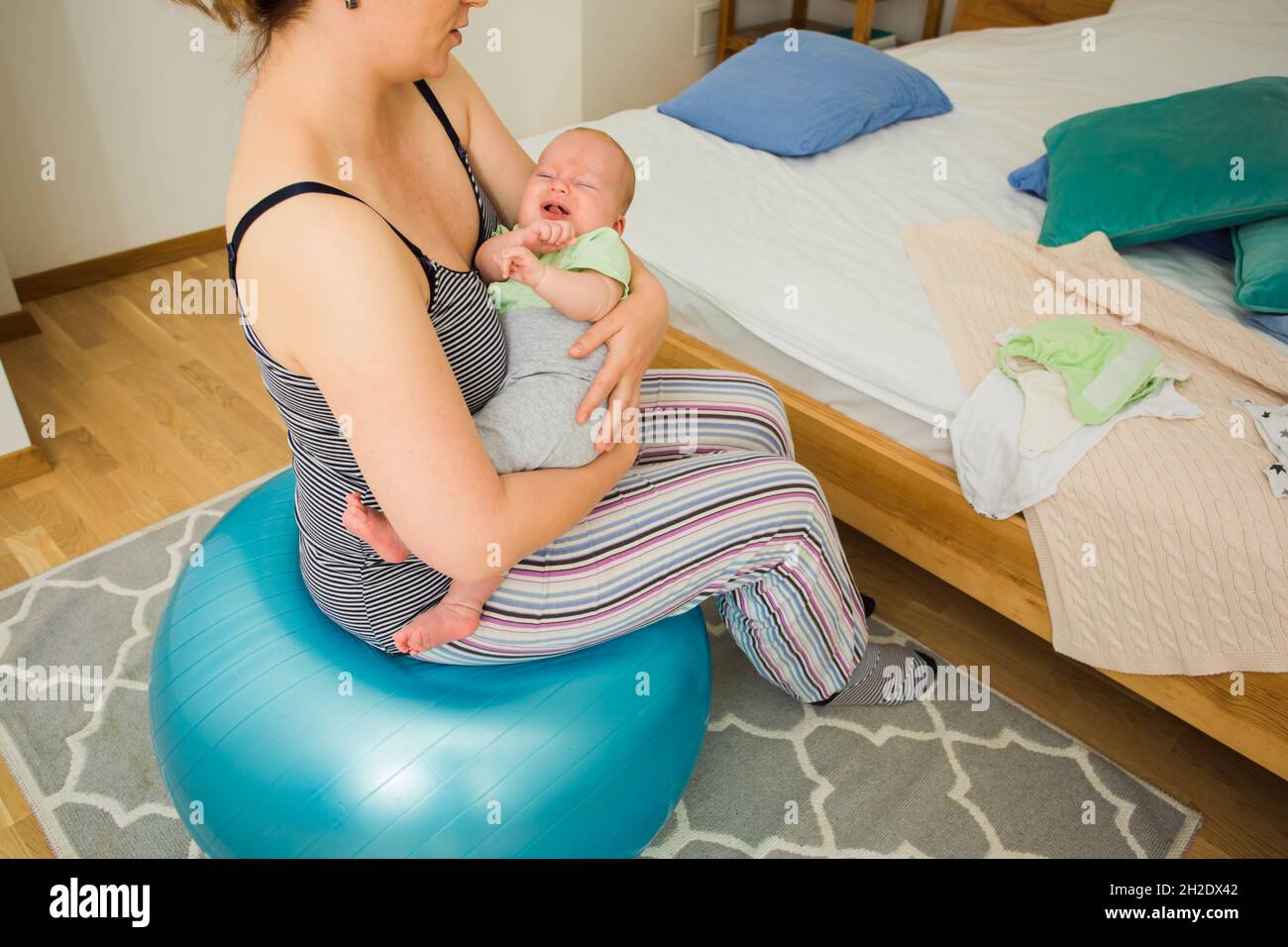 Mutter hält und schaukelt Baby auf fitball sitzen Stockfoto