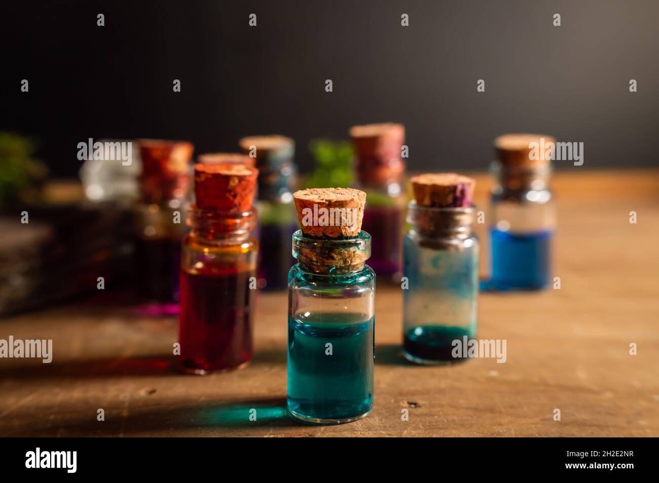 Nahaufnahme einer kleinen Glasstopfflasche, gefüllt mit blauer Flüssigkeit. Im Hintergrund weitere kleine Flaschen, die mit verschiedenen farbigen Flüssigkeiten gefüllt sind. Stockfoto