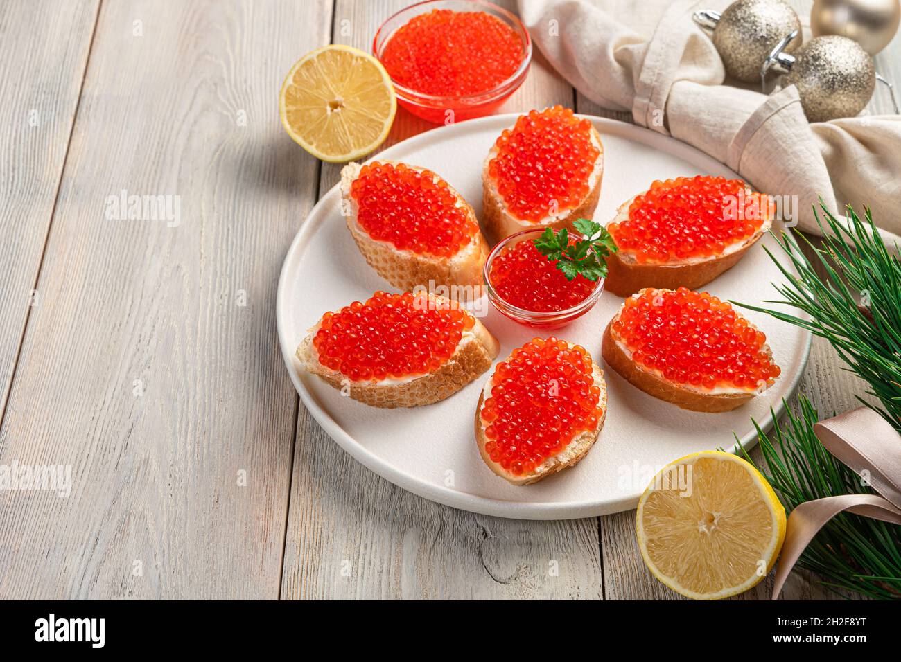 Ein Gericht mit Sandwiches mit rotem Kaviar auf hellem weihnachtlichen Hintergrund. Seitenansicht, Kopierbereich. Stockfoto