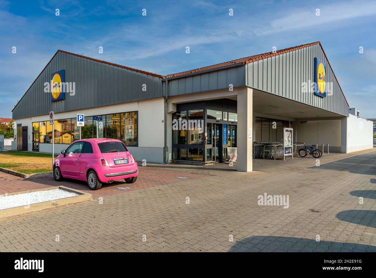 Fossano, Cuneo, Italien - 9. September 2021: LIDL Supermarkt mit pinkem 500 FIAT Auto auf dem Parkplatz, Lidl Stiftung & Co. KG. Stockfoto