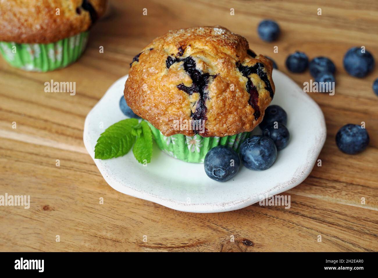 Hausgemachter Blaubeer-Muffin auf Beilagenteller, garniert mit Heidelbeeren und frischem Minzblatt Stockfoto
