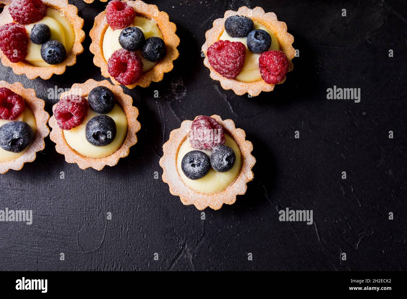 Köstliche Blaubeer-Tartalets mit Vanillecreme und frischen Himbeerbeeren Stockfoto