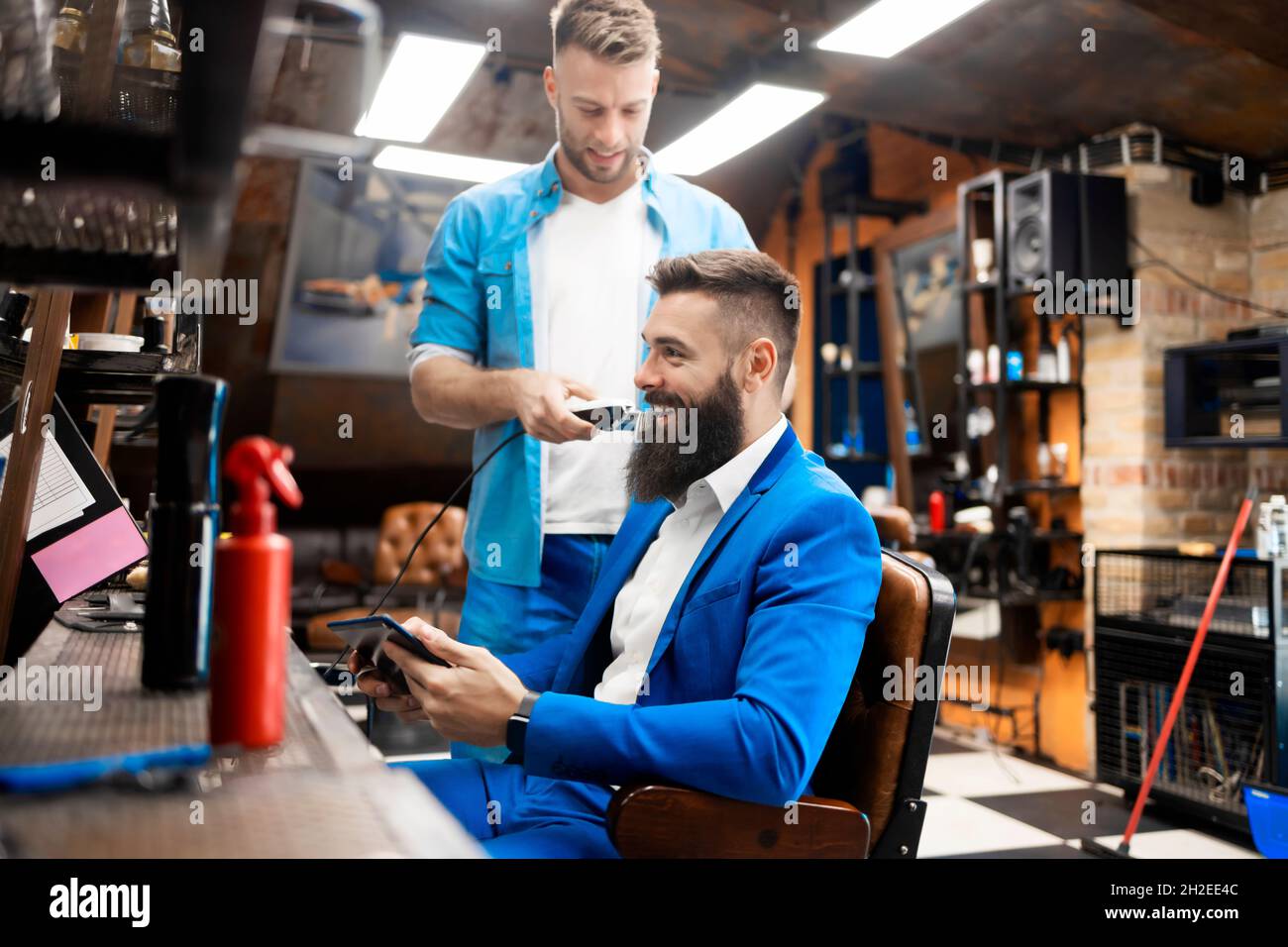 Ein Mann, der seinen Bart in einem professionellen Friseurladen beschneiden lässt Stockfoto