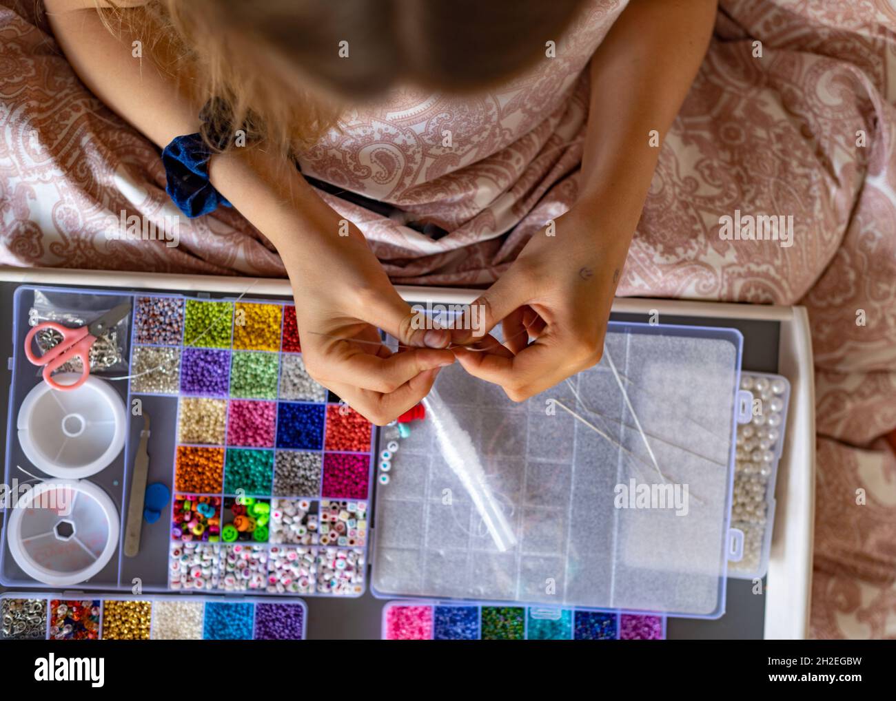 Draufsicht Bild eines Mädchens versucht, ein Armband mit einer Reihe von Sicken Kit liefert zu machen; Handwerk Stockfoto