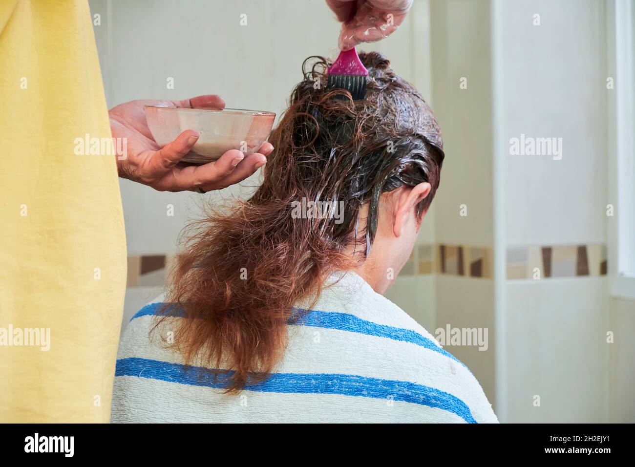 Nahaufnahme eines Mannes, der zu Hause die Haare seiner Frau färbt. Stockfoto