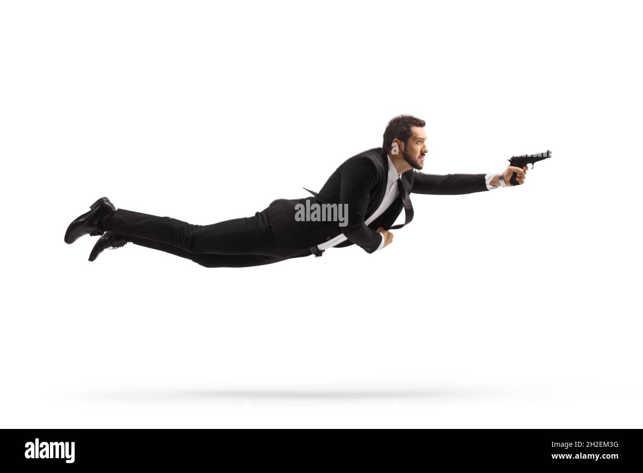 Ganzkörperaufnahme eines Mannes in einem Anzug, der fliegt und eine Waffe auf weißem Hintergrund hält Stockfoto