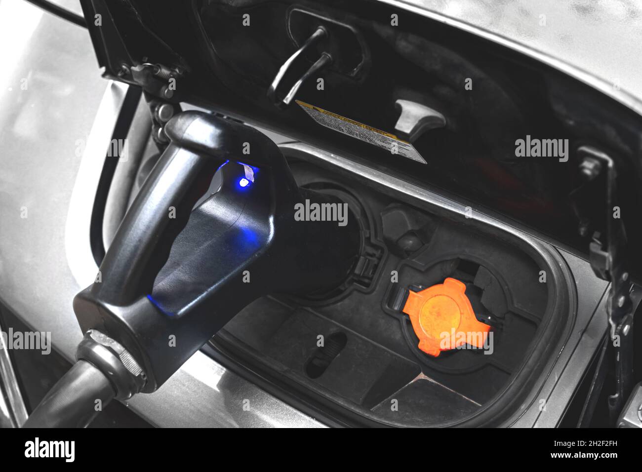 Hybrid-Auto-Ladegerät mit Netzteil in ein Elektroauto gesteckt, Nahaufnahme Bild Stockfoto