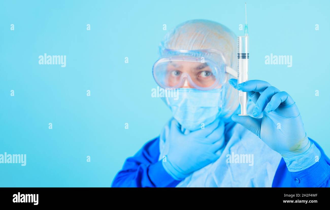 Arzt in Schutzmaske, Brille und Handschuhe mit Spritze mit Impfstoff. Impfung gegen Viren. Stockfoto