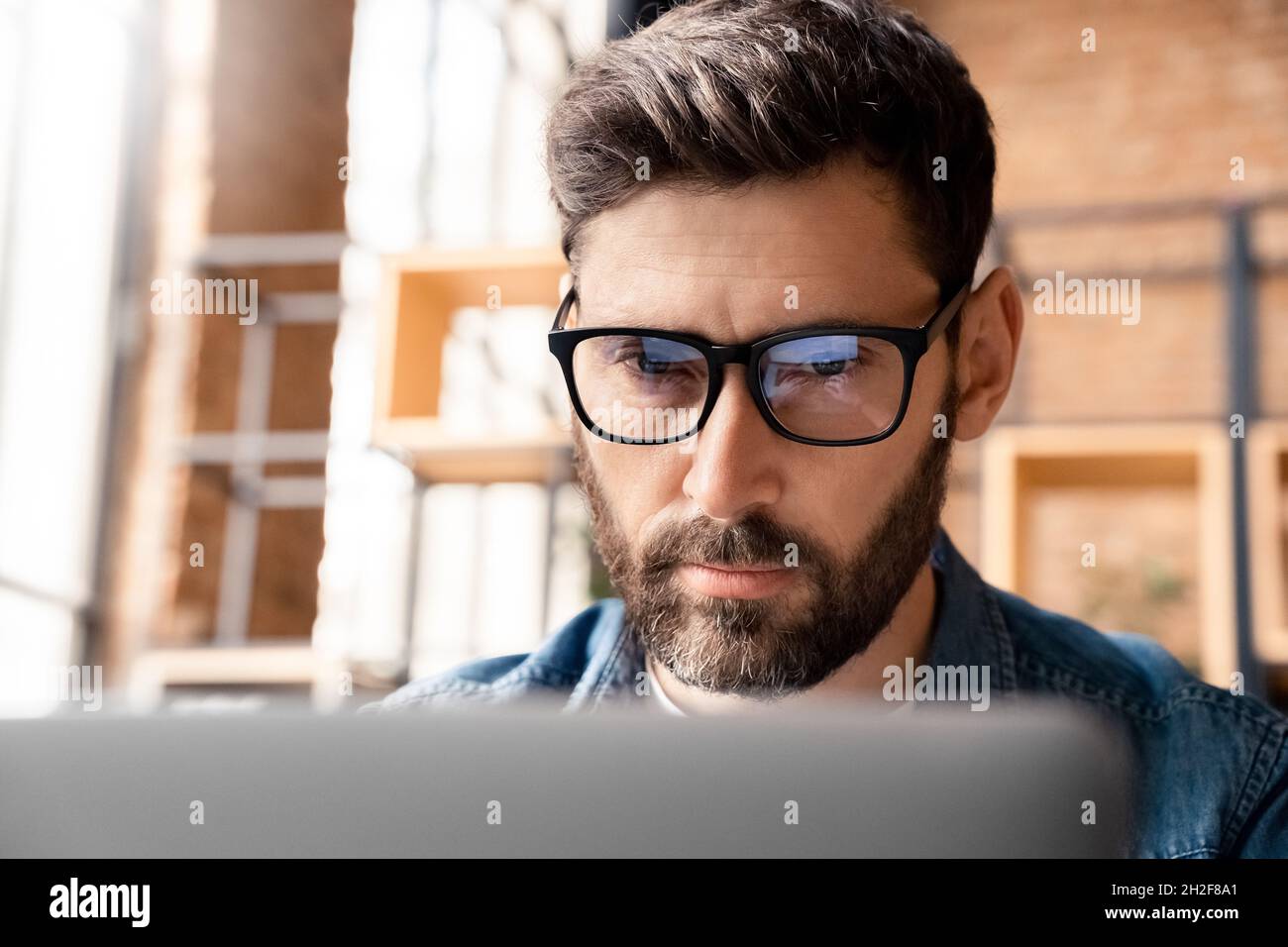 Nahaufnahme fokussierter Geschäftsmann mit Computerbrille und Blick auf den Laptop-Bildschirm Stockfoto