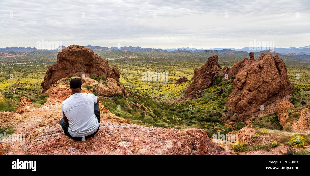 Schwarzer Mann, der die Aussicht vom Flatiron in den Superstition Mountains vom Treasure Loop Trail aus betrachtet. Wandern in der Wüste von Arizona. Stockfoto