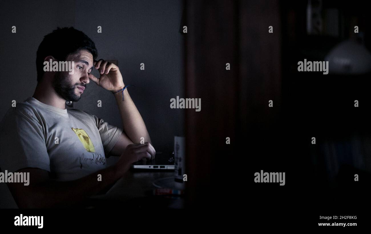 Hart arbeitender Mann hat Schwierigkeiten, nachts weiterhin an einem Laptop zu arbeiten Stockfoto