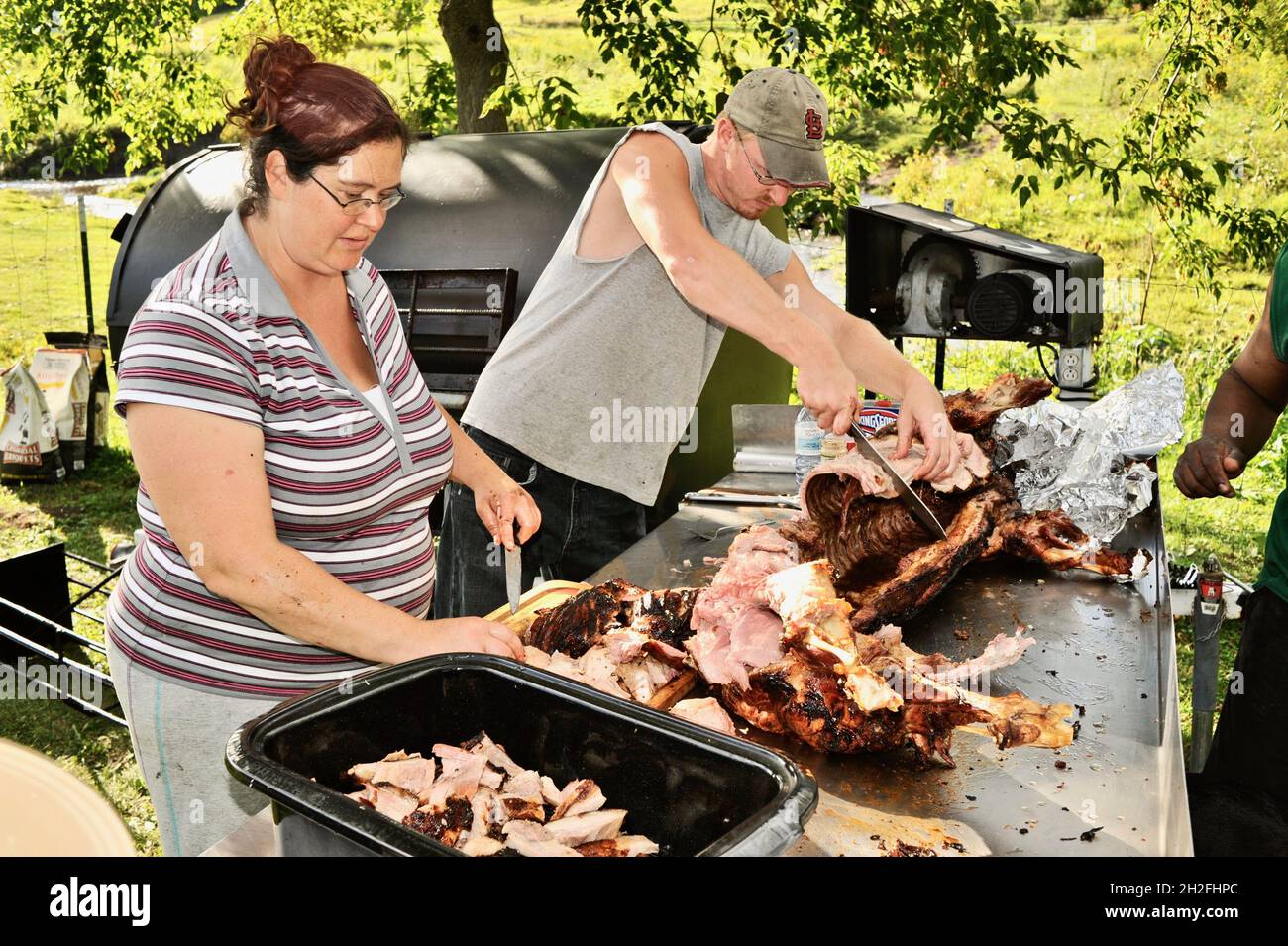 Zubereitung und Spieß-Rösten von ganzen Schwein draußen auf einem Grill, über Holzkohle, auf einer Farm im Mittleren Westen, Blanchardville, Wisconsin, USA Stockfoto