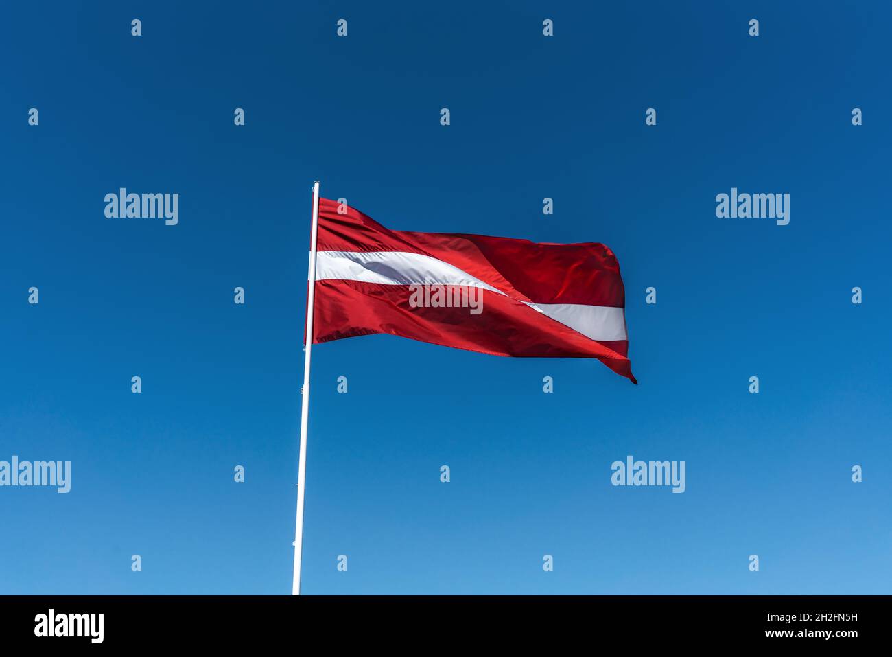 Lettische Nationalflagge mit blauem Himmel - Lettland Stockfoto