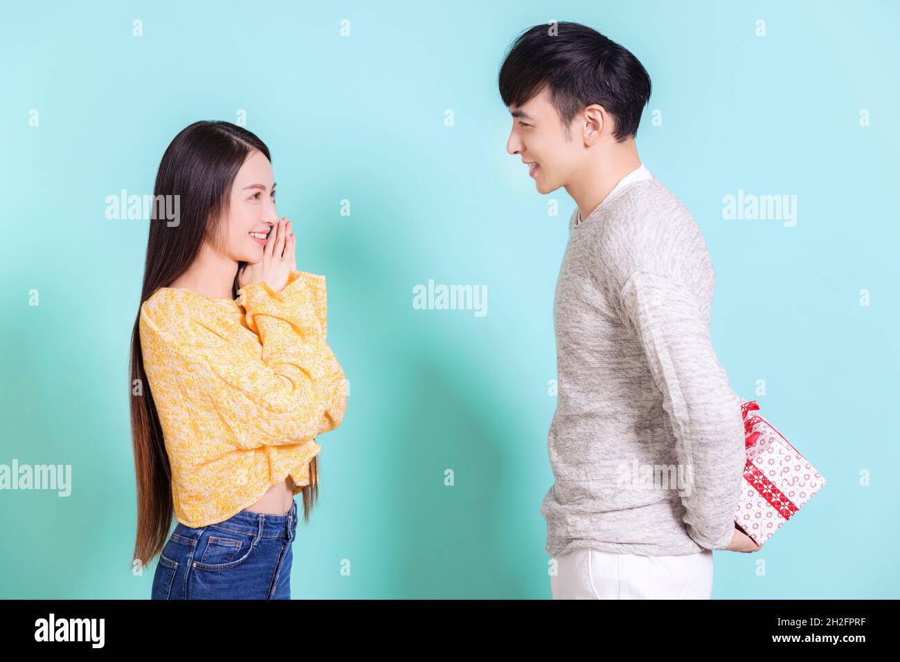 Junger Mann, der der Frau ein Überraschungsgeschenk gibt.isoliert auf blauem Hintergrund. Stockfoto
