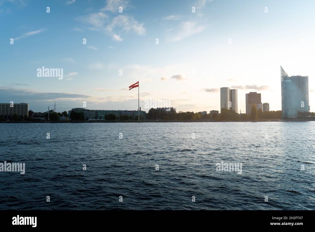 Blick auf die Skyline des Westjordanlandes von Daugava (Pardaugava) und der lettischen Flagge - Riga, Lettland Stockfoto