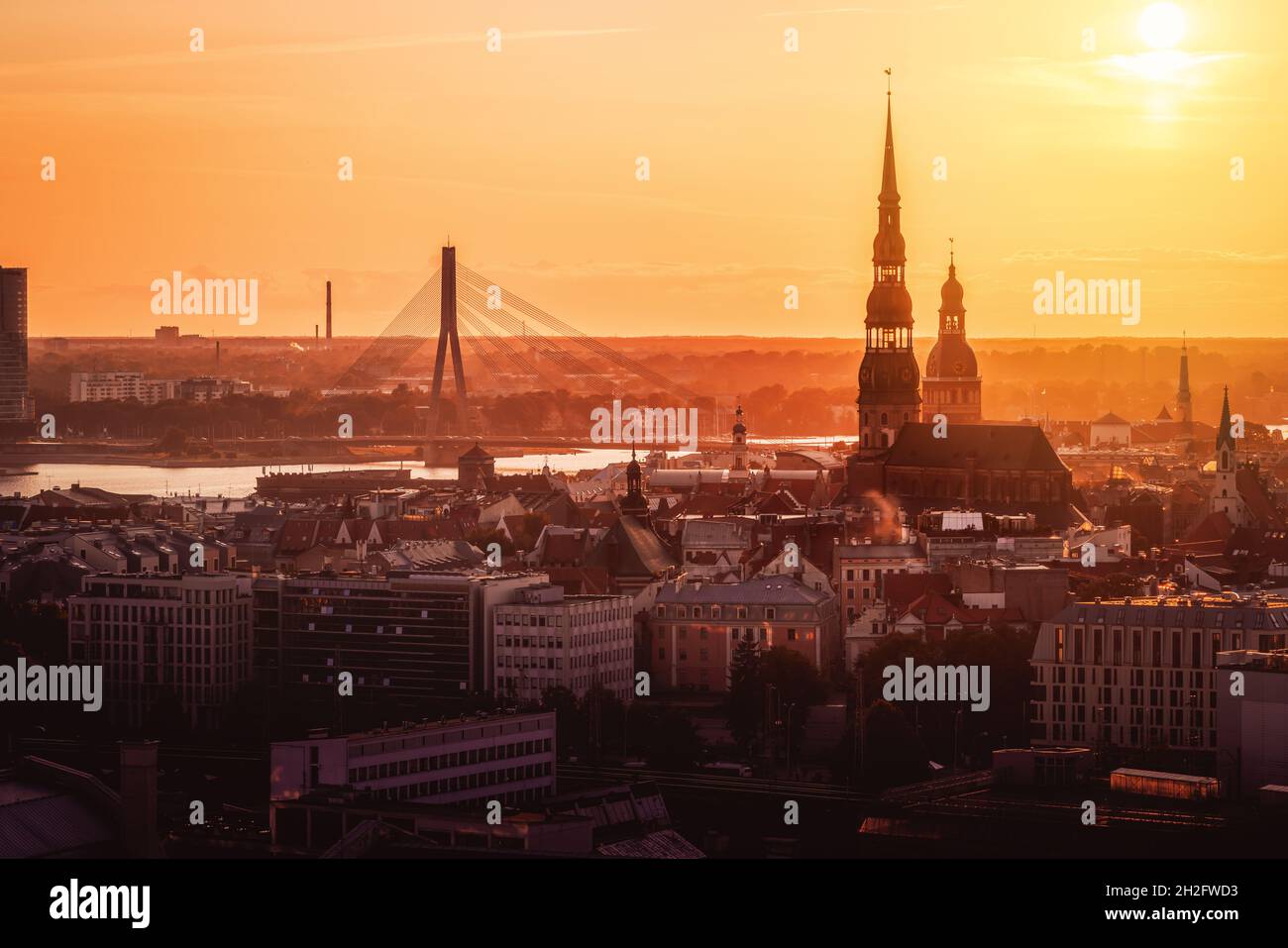 Luftaufnahme von Riga bei einem goldenen Sonnenuntergang mit der Peterkirche, der Rigaer Kathedrale und der Vansu-Brücke - Riga, Lettland Stockfoto