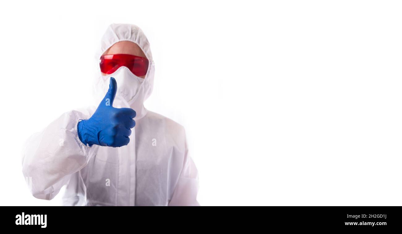 Der Arzt in einem Anzug, der sich vor einer Virusinfektion schützte, hob seinen Daumen hoch. Stockfoto