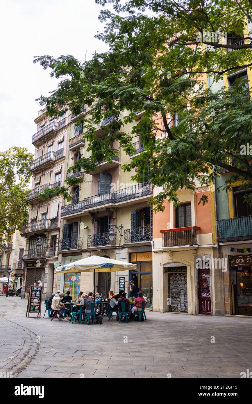 Barcelona, Spanien - 23. September 2021: Street Cafe in den Straßen von Barcelona. Menschen, die unter Sonnenschirmen sitzen und Kaffee oder Wein genießen. Stockfoto