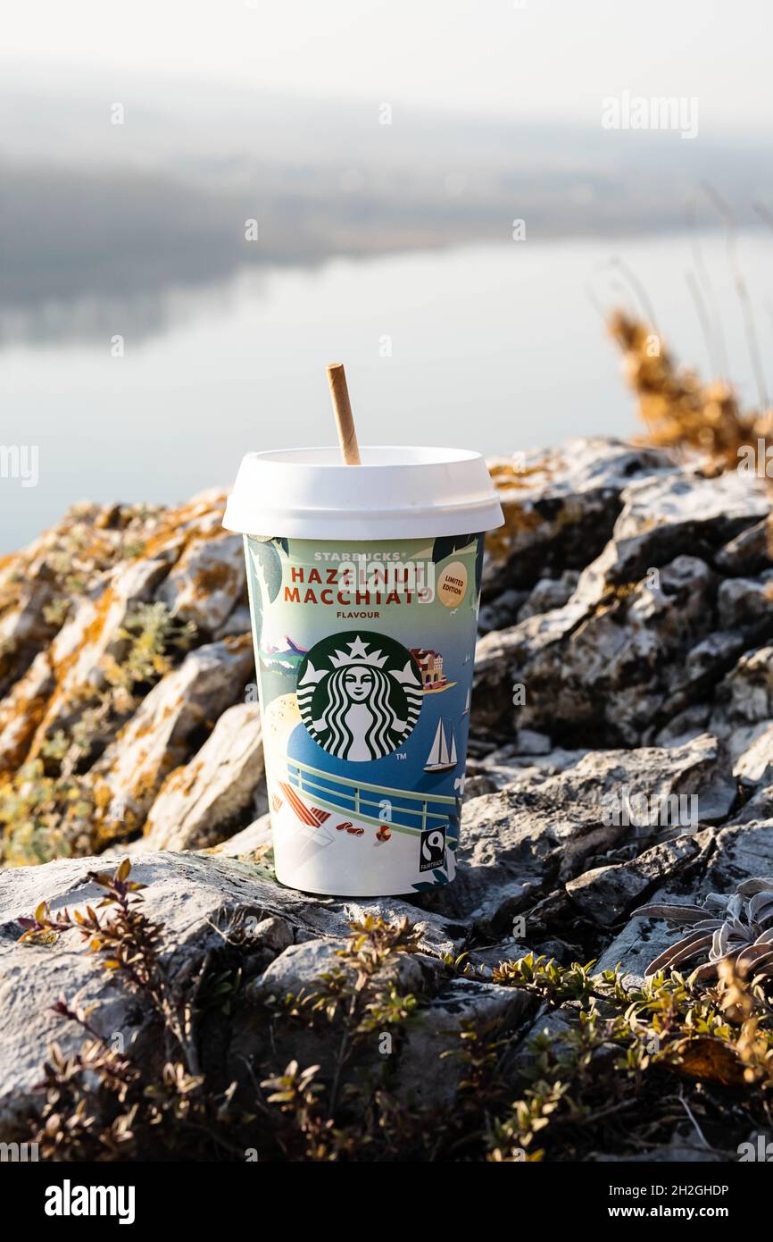 Kemerowo, Russland - 17. Oktober 2021: Starbucks zu gehen Kaffeetasse auf malerischen Hintergrund der Natur. Haselnuss Macchiato Kaffeetasse, Nahaufnahme. Stockfoto