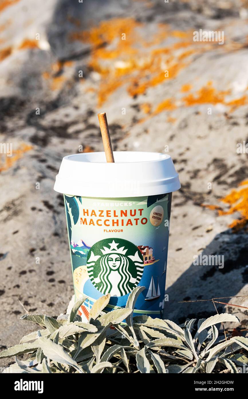 Kemerowo, Russland - 17. Oktober 2021: Starbucks zu gehen Kaffeetasse auf malerischen Hintergrund der Natur. Haselnuss Macchiato Kaffeetasse, Nahaufnahme. Stockfoto